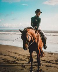 Woman riding horse on beach