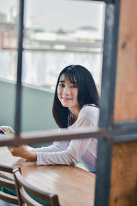 Portrait of a smiling young woman sitting on table