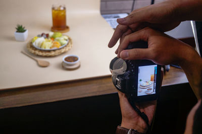Midsection of man photographing food on table