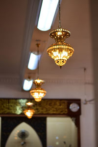 Low angle view of illuminated pendant light hanging from ceiling
