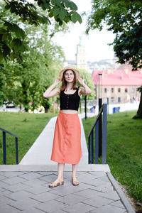 Full length portrait of woman standing on footpath
