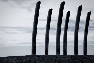 Close-up of wooden posts on beach against sky