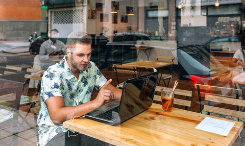 Midsection of man using mobile phone while sitting on table