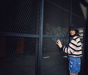 Portrait of girl standing against fence