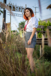 Full length of a smiling young woman standing on field