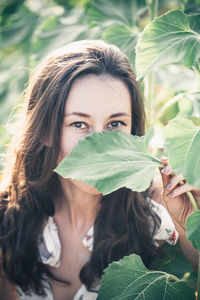 Portrait of young woman holding leaves outdoors