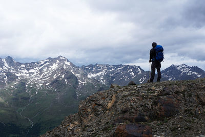 Rear view of man standing on mountain against sky