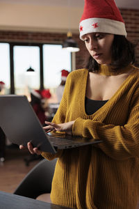 Rear view of woman using laptop while sitting at home