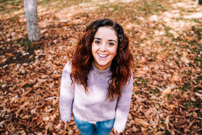 Portrait of smiling young woman standing in autumn leaves