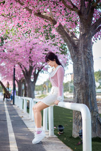 Full length of woman with pink cherry blossoms in park