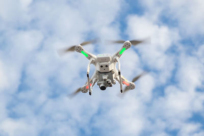 Low angle view of drone flying in cloudy sky