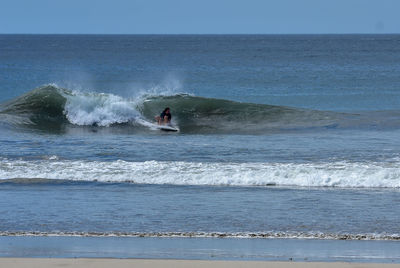 Woman surfing in sea against sky