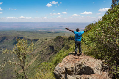 Rear view of man standing on rock against volcanic crater on mount suswa, kenya 