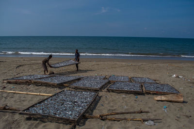 Men standing on beach against sky