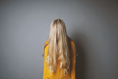  girl face covered with hair standing against gray background