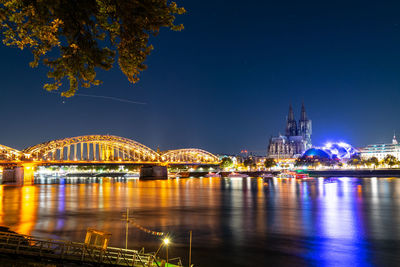 Illuminated bridge over river at night