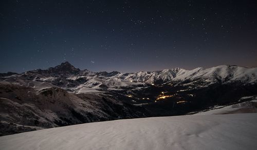 Scenic view of snowcapped mountains against sky at night