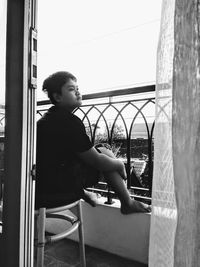 Side view of young boy looking through window