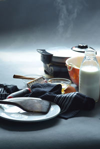 Waffle iron steaming as a waffle cooks, bowl of batter, milk bottle, egg, cinnamon sticks