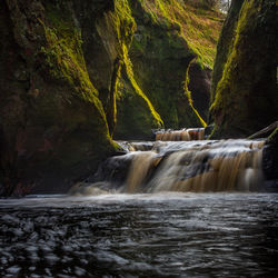 Scenic view of waterfall by sea