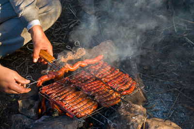Midsection of man preparing food on barbecue grill