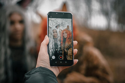 Midsection of person photographing with mobile phone