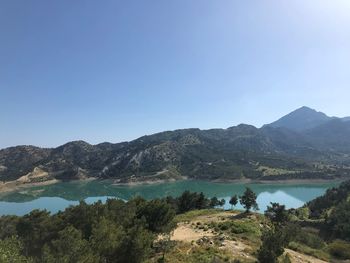 Scenic view of lake and mountains against clear blue sky