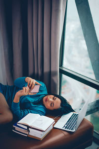 Woman reading book while sitting on table at home