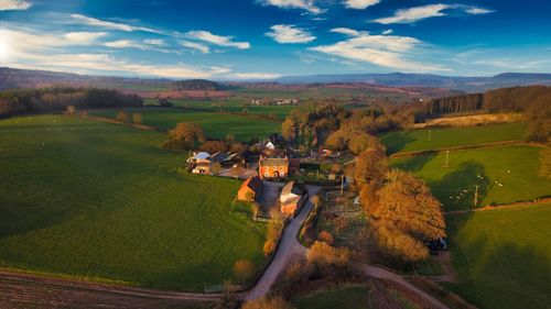 Scenic view of agricultural field against sky, including a single house.