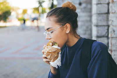 Young woman eating ice cream on street