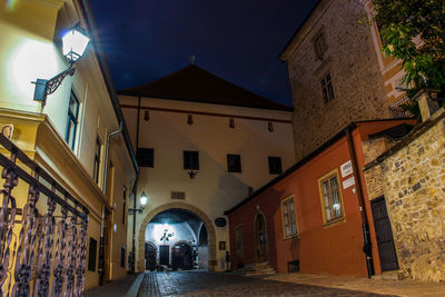 Low angle view of illuminated street amidst buildings