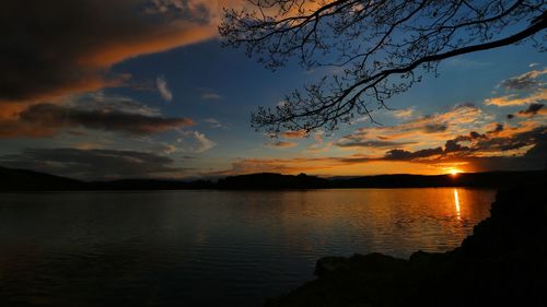 Scenic view of lake against dramatic sky during sunset