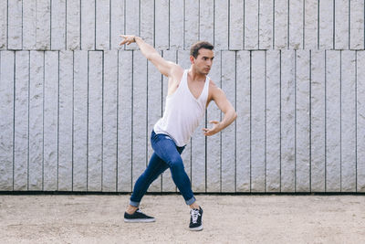 Full length of man jumping while dancing against wall