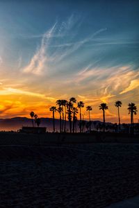 Silhouette people on beach against sky during sunset