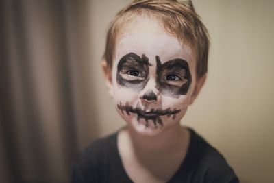 Close-up portrait of boy with painted face at home during halloween