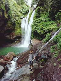 Man standing by waterfall in forest