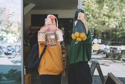 Couple showing groceries in mesh bags outside store