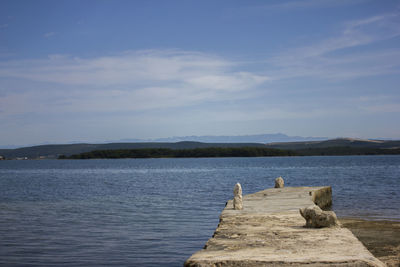 View of pier in lake against cloudy sky