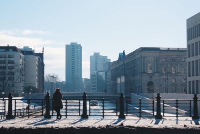 People standing on railing against buildings in city