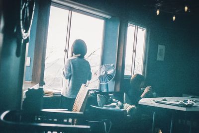 Rear view of woman sitting on table