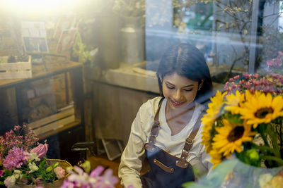 Smiling florist in store seen through window