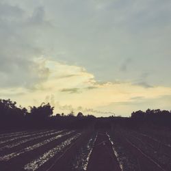 Road passing through landscape against cloudy sky
