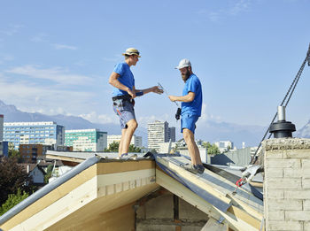 Men standing on rooftop of house at construction site