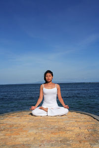 Woman doing yoga against sea and sky
