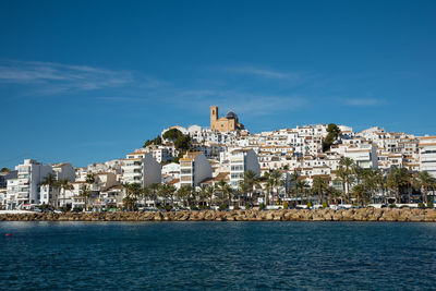 Houses by sea against sky in town