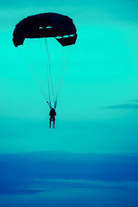 Person paragliding in sea against sky