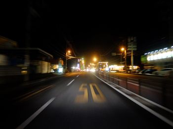 Road passing through illuminated city at night