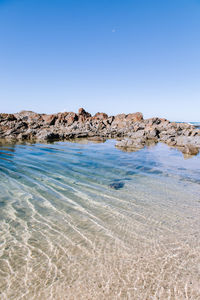 Scenic view of beach against clear blue sky