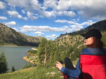 Midsection of woman against lake and mountains against sky