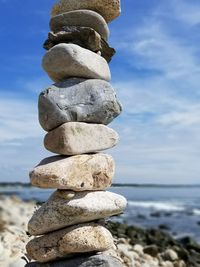 Stack of pebbles on beach against sky